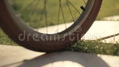 自行车车轮在绿色的草地上向前移动。 双腿在自行车旁行走